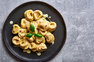 Tortellini ravioli creamy pasta. Italian ravioli pasta with pumpkin and basil on rustic background