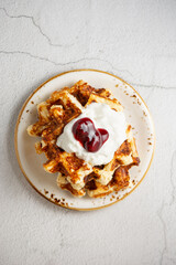 Top view Belgian cottage cheese waffles with sour cream and cherry jam on a plate on a concrete white background. Sweet breakfast.