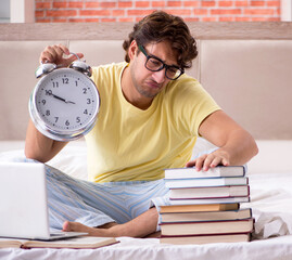 Young student studying in bed for exams