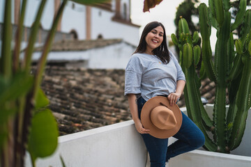 Chica guapa joven apoyada en pared blanca con iglesia de fondo en azotea de un hotel estilo soho