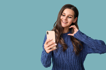 Fototapeta premium Beautiful young woman texting with her boyfriend on blue background