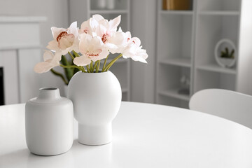 Vases and beautiful orchid flowers on white table