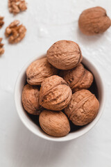 Whole walnuts in a white bowl on a white background. Healthy eating concept.