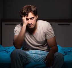 Young handsome man suffering from insomnia in bed