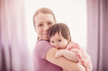 Mother holding in her hands cute daughter indoors.