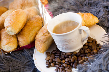 A cup of coffee and delicious croissants on a fluffy blanket