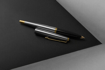 Luxurious fountain pen with the lid next to it on a black and gray background