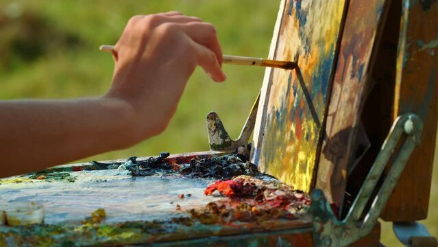 Painter hand drawing oil paints outdoor. Unknown artist painting canvas closeup