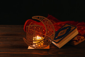 Arabic candle holder with glowing candle, Quran and carpet on dark background
