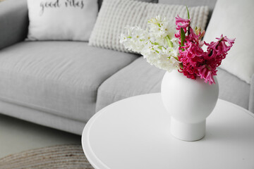 Vase with beautiful hyacinth flowers on table in living room