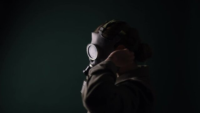 Pouse military in a gas mask, apocalypse, nuclear weapons, atomic explosion of a station, chemical and nuclear weapons protection. Girl in a mask on a green background, war