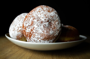 Polish pączki (deep-fried doughnuts). Celebrating Fat Thursday (Tłusty czwartek) feast, traditional day in Poland. Pączek food, powdered sugar topped and filled with rose hip jam.