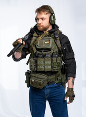 airsoft player in full gear is ready to play. a man in an outfit, in headphones, a bulletproof vest, with a backpack and a belt with additional shells. on a white background.