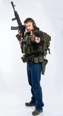 the airsoft player puts his rifle on his shoulder and aims at us with his fingers. a man in an outfit, in headphones, a bulletproof vest, with a backpack on a white background.