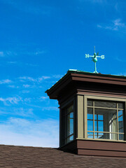 green weather vane on a roof with blue sky background