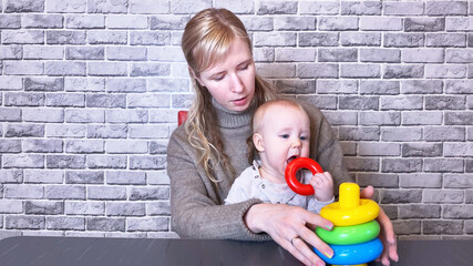 Mother playing with little kid on gray brick wall background. Copy space for text