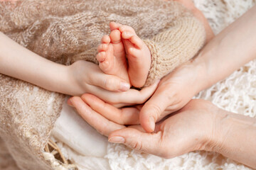 Baby feet in parents hands. Tiny Newborn Baby's feet on ffamily hands closeup. Mom, dad and they child. Happy Family concept. Beautiful conceptual image of Parenthood