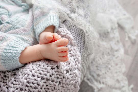 Tiny foot of newborn baby. Soft newborn baby feet against a beige  blanket. Baby feet with toes curled up. Copy space