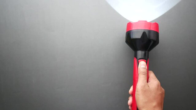 hand holding a tourch light against yellow background,