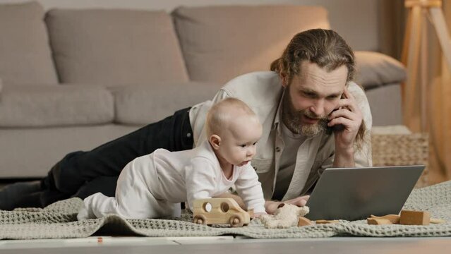Caucasian multitasking father working from home with laptop quarantine with little baby infant newborn lying on floor talking phone solve business problems. Exhausted parent with hyperactive child