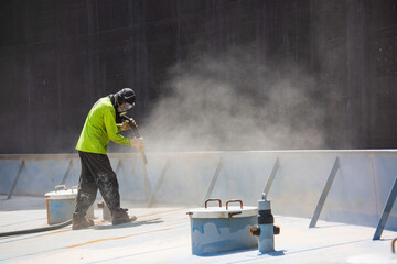 Male worker surface corrosion plate preparation by sand blasting of tank