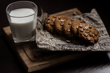 Peanut cookies on a newspaper and a wooden board and a glass of milk. Dark and Moody. Light breakfast. High quality photo