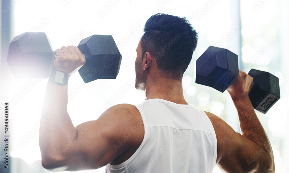 Poster its a commitment he makes every day. rearview shot of a handsome young sportsman working out with du