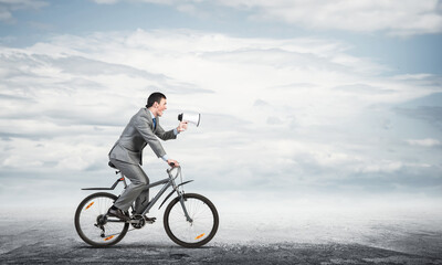 Fototapeta premium Businessman with megaphone on bike
