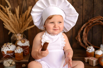 A little funny girl in a white cook suit on a dark wooden background