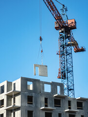 Construction of panel high-rise buildings. Tower crane delivers a concrete slab at a construction...