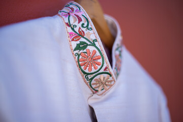 Closeup of traditional Indian wedding clothing for a groom handing on a wooden hanger