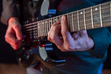 Male hands playing electric guitar. Musician man with black guitar at a rock concert