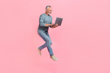 Photo of charming retired man wear grey shirt jumping chatting gadget empty space isolated pink color background