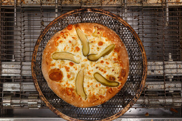 Freshly baked pizza with cucumbers and mozzarella comes out of modern conveyor oven