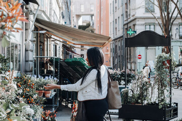 Fototapeta na wymiar Lifestyle portrait of Hispanic woman walking with bag on street with fruit bowls in city of Lyon