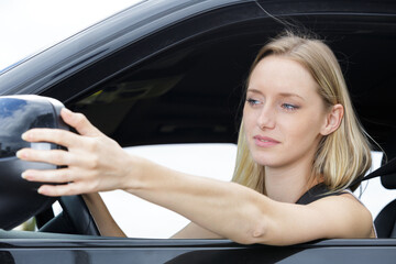 female driver adjusting the side mirror of car