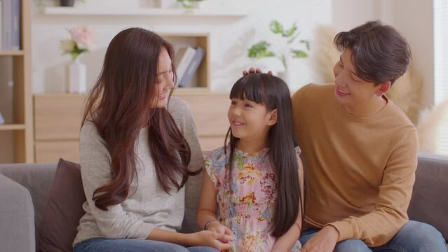 Little girl told happiness story to her mom and dad with positive and proud emotional.Asian Daughter tell a story to mother and father father touching her head with love at cozy home.Good moment