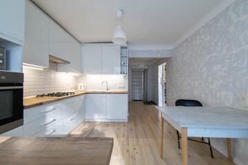 Fototapeta na wymiar interior of cozy small kitchen with wooden floor, white cabinets and solid wood worktop.