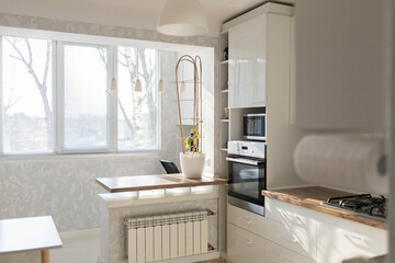 interior of a small kitchen with a balcony combined with a room, a bar counter made of a window sill. Kitchen remodeling. Work area in the kitchen with wooden floor and worktop.