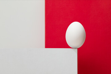 White egg on the white box. White and red background.