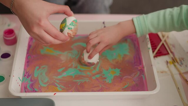Woman and girl roll eggs in oily water with Ebru decor mix
