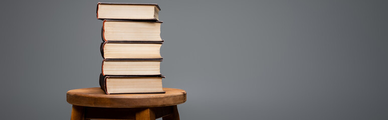 books stacked on wooden stool isolated on grey with copy space, banner.