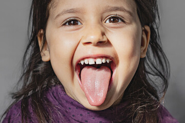 Close-up portrait of an emotional preschooler sticking out his tongue and showing grimaces