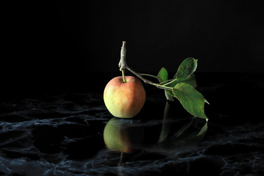 Close-up shot of an apple and its reflection on a black marble table isolated on a black background