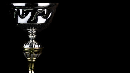 Shiny cool silver trophy isolated on a black background with copy space