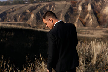 Stylish manly groom in black suit