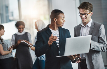 Just another busy average day in the office. Shot of a group of young cheerful businesspeople browsing on digital devices while working together in the office at work.