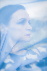 portrait of a beautiful woman behind blue veil