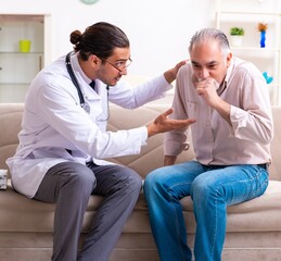 Obraz premium Young male doctor visiting old patient at home