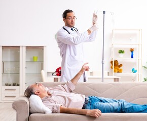 Obraz premium Young male doctor visiting old patient at home